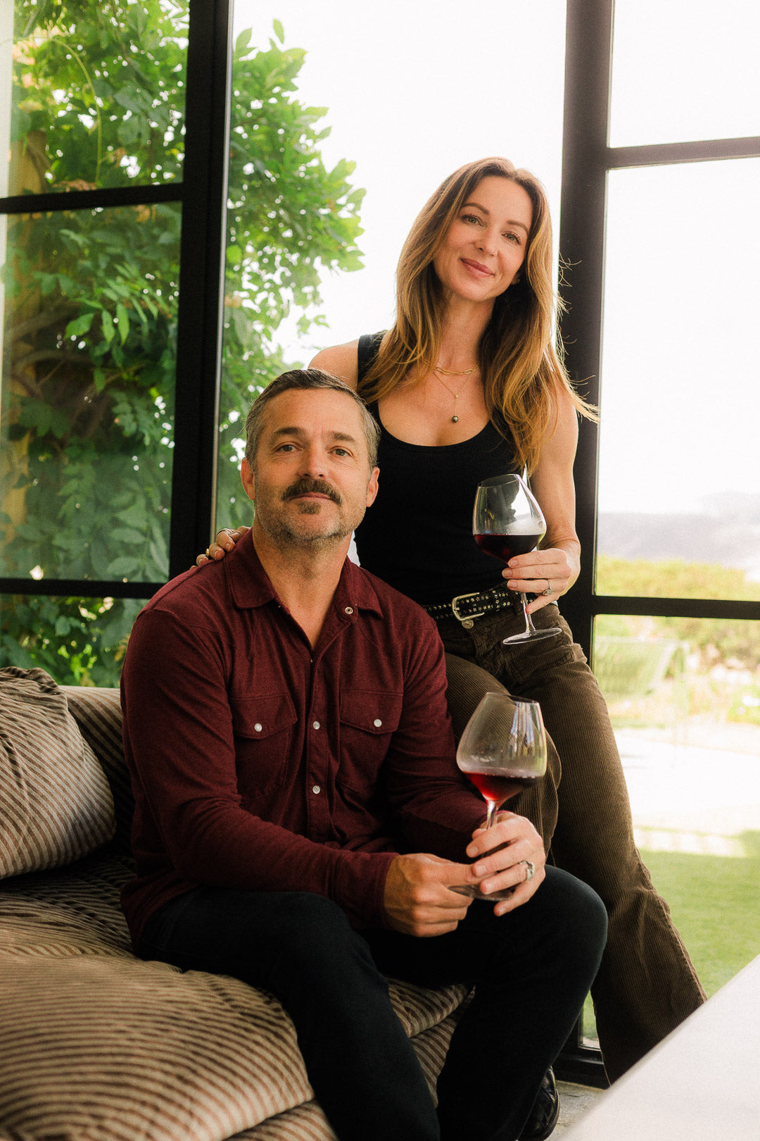 Man and woman sitting on a couch with wine glasses indoors